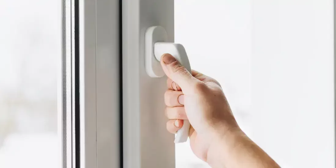A hand on a window handle ready to turn and open it
